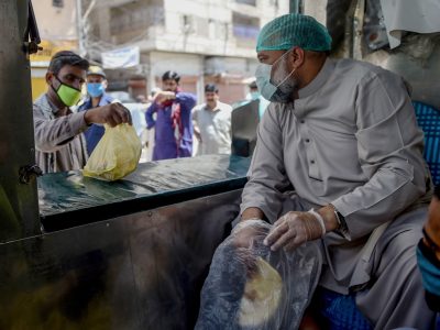 A municipal worker in Karachi hands out bags of food -- part of government efforts to help those who've lost their livelihood during Pakistan's lockdown to stem the spread of the coronavirus.